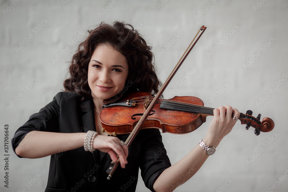 Young attractive brunette girl of Asian appearance on a white brick background with a violin in her hands. Young attractive brunette girl of Asian appearance on a white brick background with a violin in her hands.