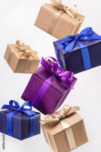Gifts in flying boxes, wrapped in blue, purple and craft paper with bow on bright background. Holidays and greeting card concept.