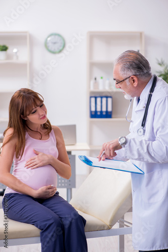 Young pregnant woman visiting old male doctor gynecologist