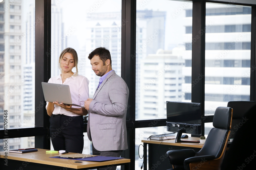 Professional Business people standing and talking or meeting or discussing with colleagues in office with using laptop computer Professional Business people standing and talking or meeting or discussing with colleagues in office with using laptop computer