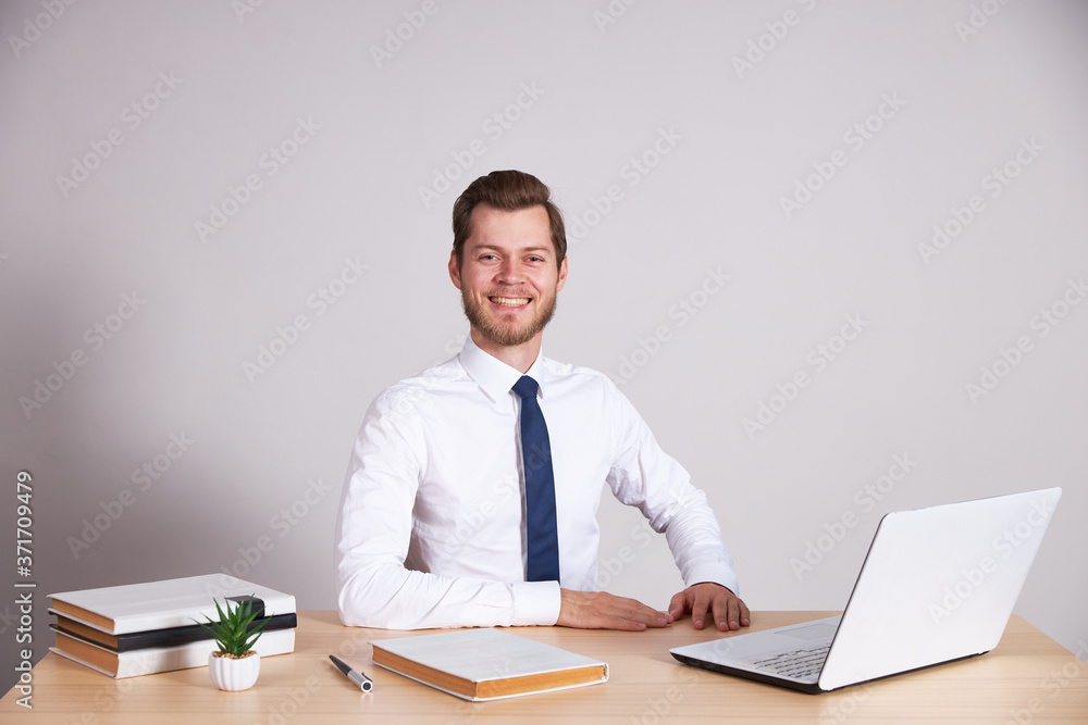 A businessman in a white shirt and blue tie sits at his desk and looks into the camera. A businessman in a white shirt and blue tie sits at his desk and looks into the camera.
