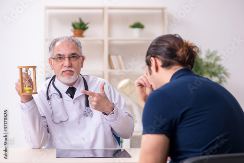 Young male patient visiting old doctor in time management concep