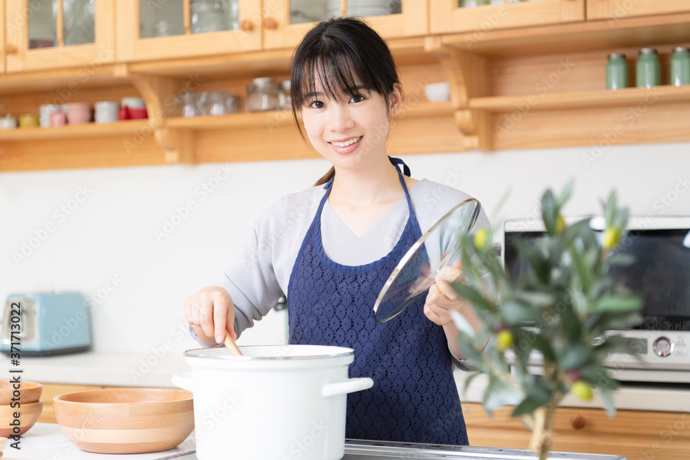 キッチンに立つエプロンを着た若い女性