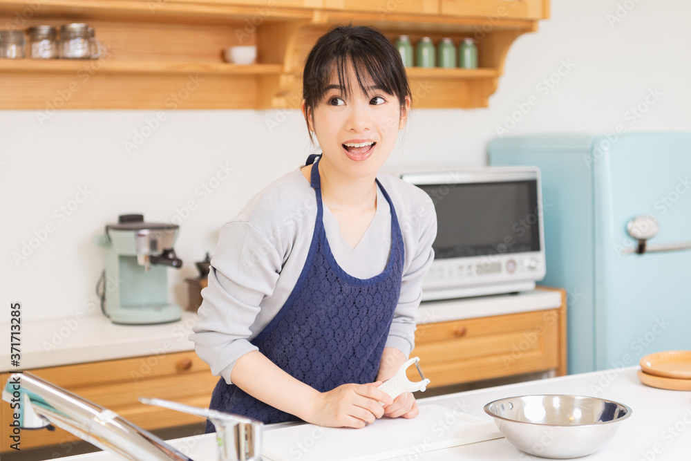 キッチンに立つエプロンを着た若い女性 キッチンに立つエプロンを着た若い女性