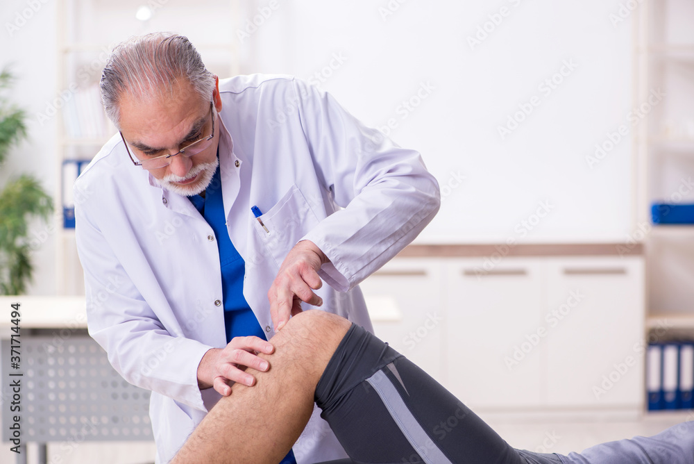 Obraz premium Young male patient visiting old doctor traumatologist