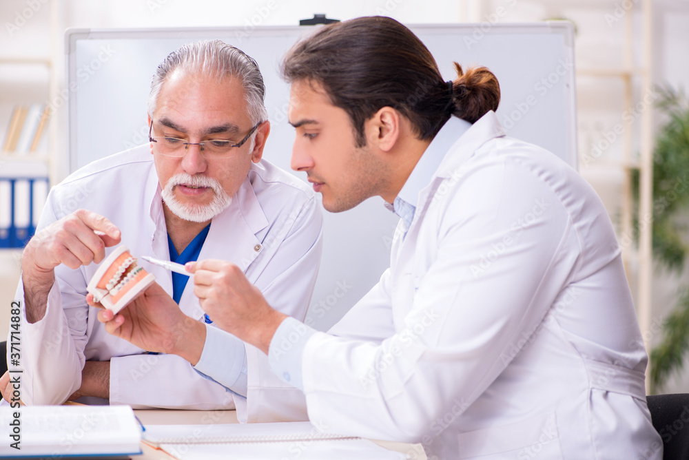 Experienced doctor dentist teaching young male assistant Experienced doctor dentist teaching young male assistant