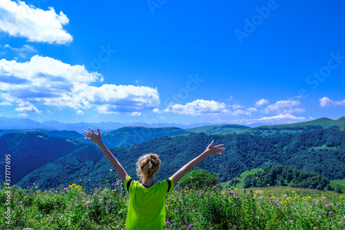 young tourist woman raising her hands up and enjoying a fantastic view on nature  forest and alpine mountains. Mountainous landscape