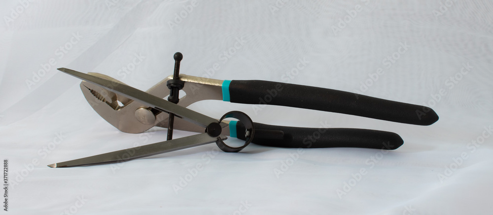 Steel drawing compasses and pliers on a white background. Steel drawing compasses and pliers on a white background.
