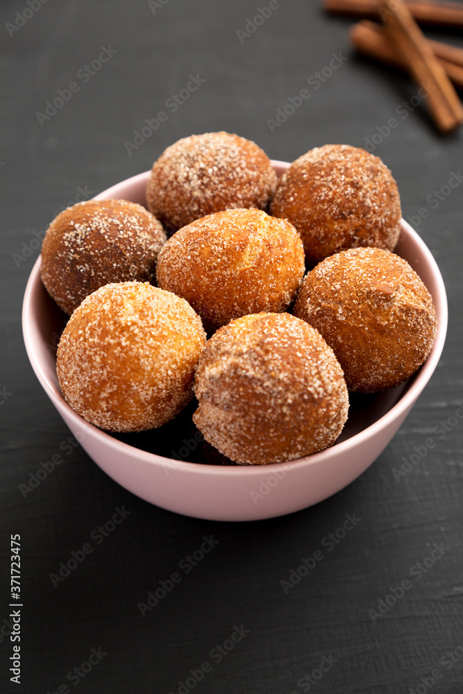 Homemade Fried Donut Holes in a pink bowl on a black surface, low angle view. Homemade Fried Donut Holes in a pink bowl on a black surface, low angle view.