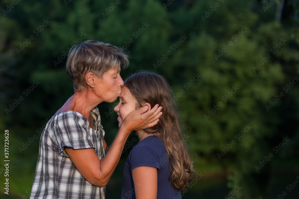 Grandmother kissing litlle granddaugther outdoor at evening Grandmother kissing litlle granddaugther outdoor at evening