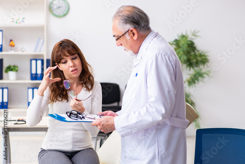 Young woman visiting old male doctor ophthalmologist