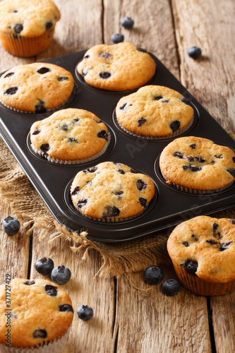 Delicious muffins with blueberries close-up in a baking dish on the table. vertical