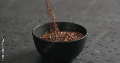 flaxseed falling into black bowl on terrazzo countertop