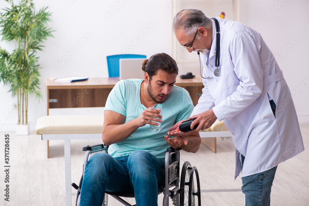 Experienced doctor and young male patient in wheel-chair Experienced doctor and young male patient in wheel-chair
