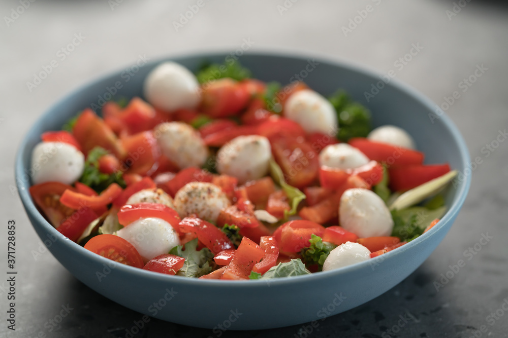 salad with mozzarella, tomatoes and bell pepper in blue bowl on kitchen countertop salad with mozzarella, tomatoes and bell pepper in blue bowl on kitchen countertop