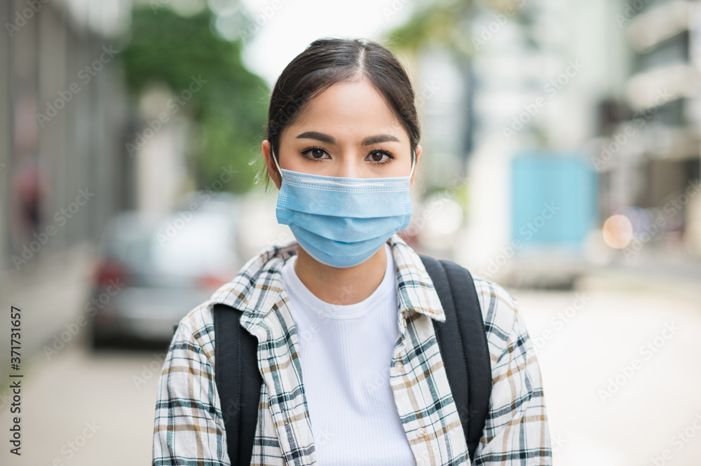 New normal of traveler. Alone young asian beautiful woman travel in holiday with backpack and wearing protection mask virus for safety trip. She walking alone in the city. New normal of traveler. Alone young asian beautiful woman travel in holiday with backpack and wearing protection mask virus for safety trip. She walking alone in the city.