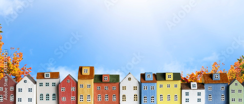 Colorful miniature house in a row on blue sky background. Urban city skyline background banner. 