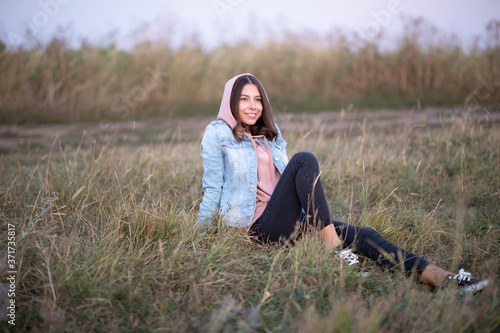 Young European woman or student is sitting  in the evening in a field