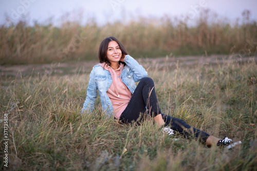 Young European woman or student is sitting  in the evening in a field