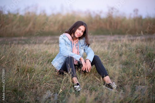 Young European woman or student is sitting  in the evening in a field