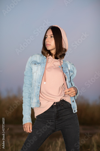 Young European woman or student is posing  in the evening in a field