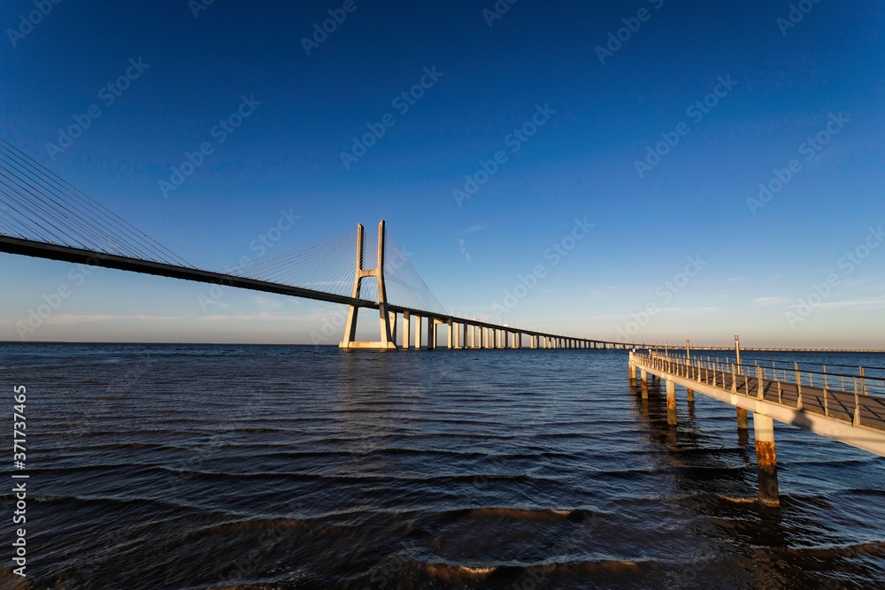 Obraz premium The Vasco da Gama Bridge is a cable-stayed bridge flanked by viaducts and spans the Tagus River in Parque das Nações in Lisbon, the capital of Portugal. It is the longest bridge in the European Union