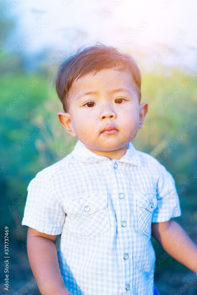 Asian little boy is looking at the camera in the grass field. Asian little boy is looking at the camera in the grass field.
