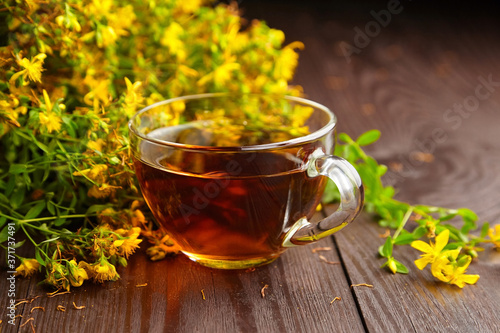 Cup with Hypericum perforatum, St Johns wort or tutsan plant drink with fresh flowers.
