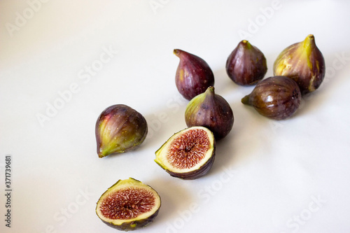 Ripe figs, purple green. Whole fruits and cut with red flesh and seeds. Grey-blue background.