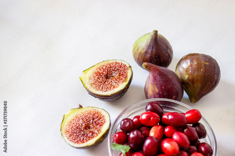 Ripe figs, purple green, whole fruits and cut with red flesh with seeds.Dogwood in a glass bowl Gray and blue background. Ripe figs, purple green, whole fruits and cut with red flesh with seeds.Dogwood in a glass bowl Gray and blue background.