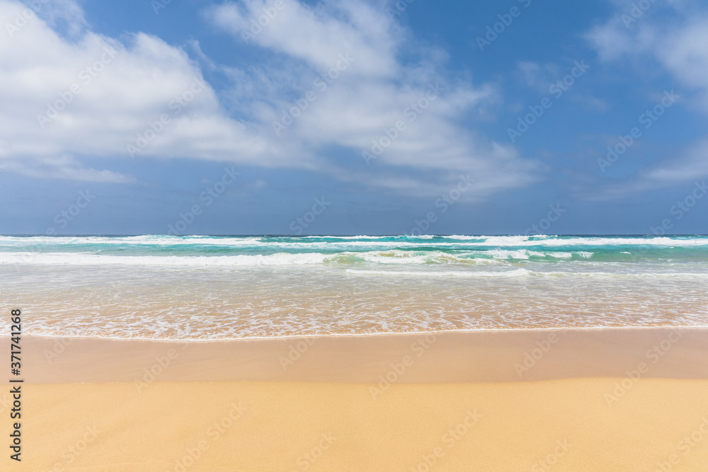 View of the ocean waves, sandy beach and sky.