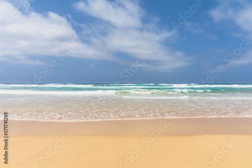 View of the ocean waves, sandy beach and sky.