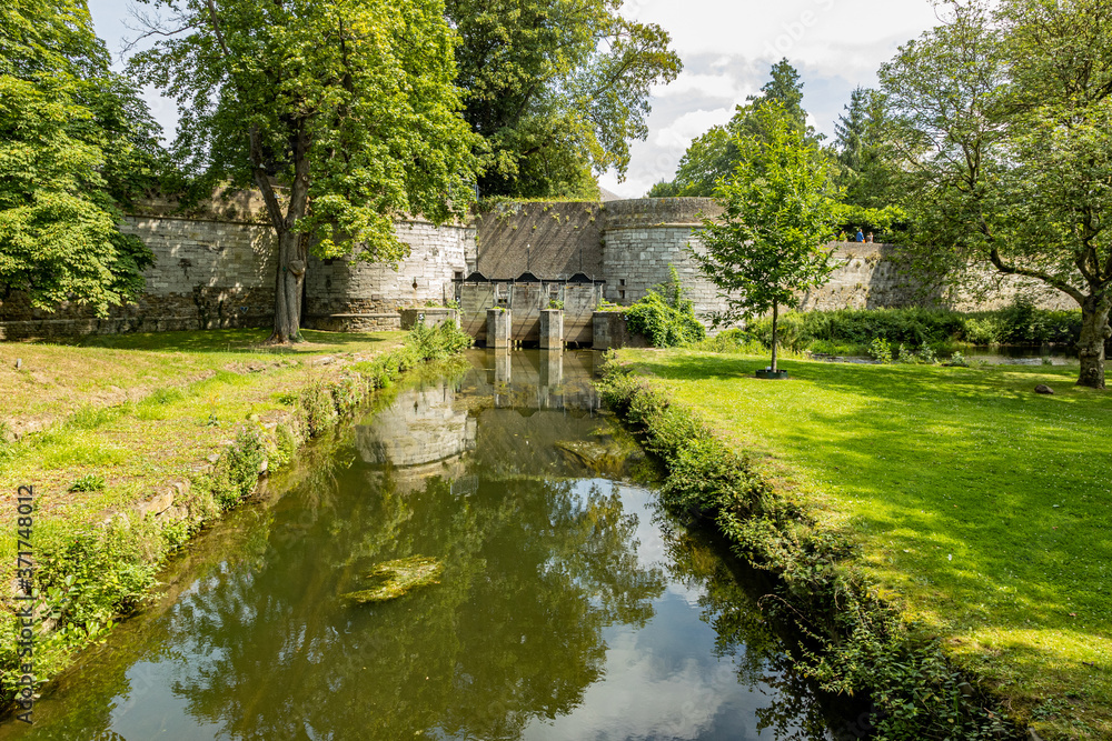 Jeker river with the water gate of the Reek (waterpoort) in the second medieval city wall of Maastricht, trees and green vegetation on a sunny summer day in South Limburg, Netherlands Jeker river with the water gate of the Reek (waterpoort) in the second medieval city wall of Maastricht, trees and green vegetation on a sunny summer day in South Limburg, Netherlands