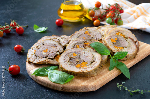Delicious meat rolls stuffed with vegetables with cherry tomatoes and basil. Festive dish.