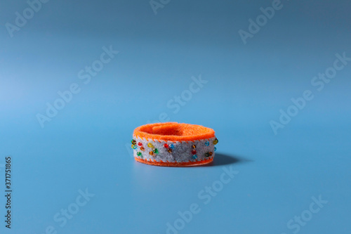 The handmade felt orange bracelet is a nice gift on the blue background