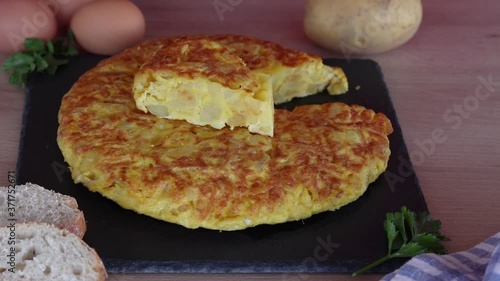 Mano con cuchillo y tenedor cortando un trozo de tortilla de patatas 