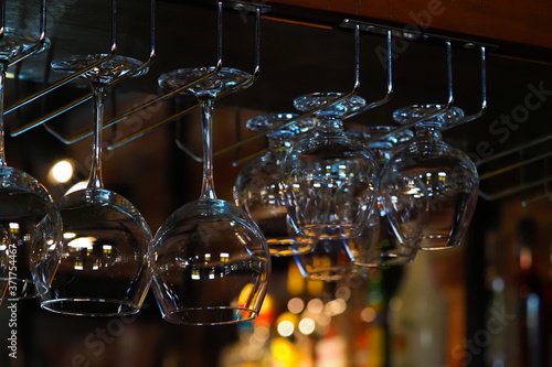 Empty glasses for wine above a bar rack. Hanging glasses in a restaurant