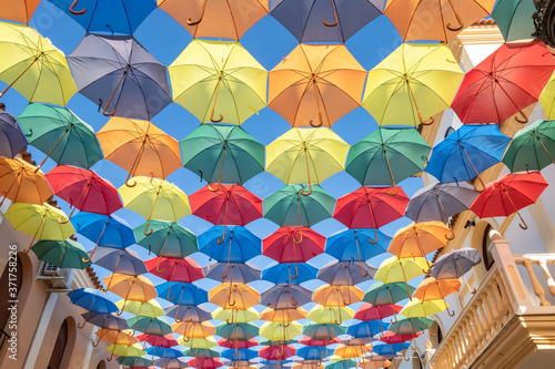 The sky is full of colorful umbrellas. Street with umbrellas in the sky in the village San Bartolome de la torre. Summer decoration and sun  protection. Huelva province  Andalusia  Spain