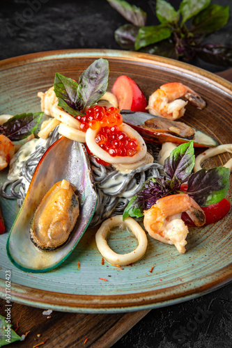 Black pasta with cuttlefish ink with seafood mussels, shrimps, red caviar and basil