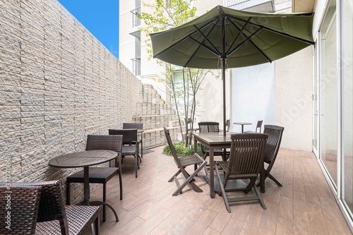 A set of wooden tables and chairs for relaxing in the garden outside the building © torsakarin