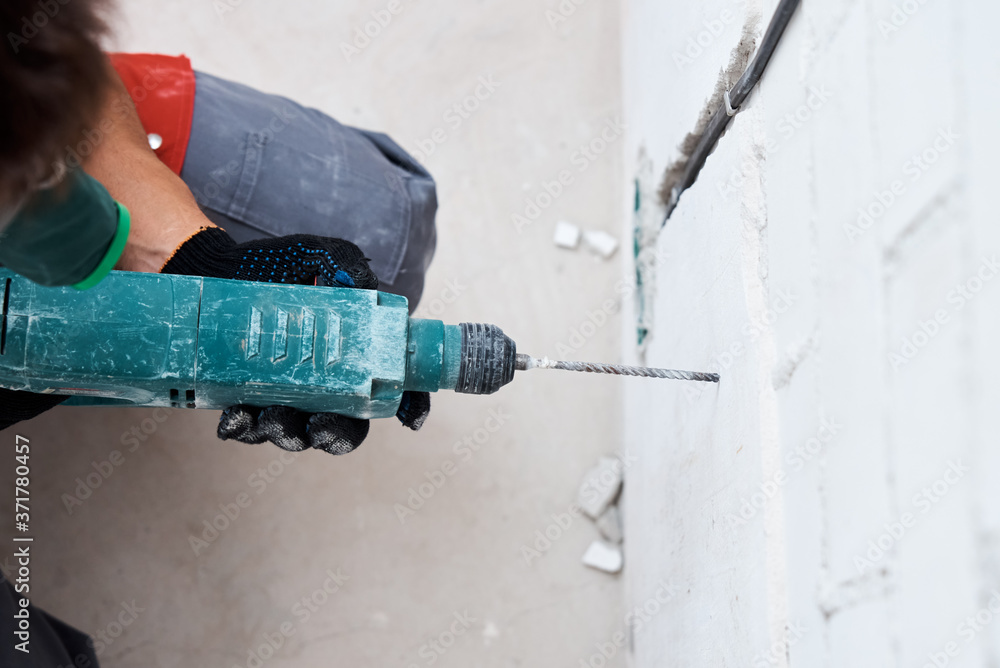 Man worker drilling wall with hammer drill, top view