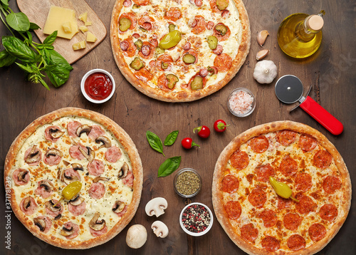 Three hot cheese pizzas with chorizo and mushroom on rustic wooden table with ingredients