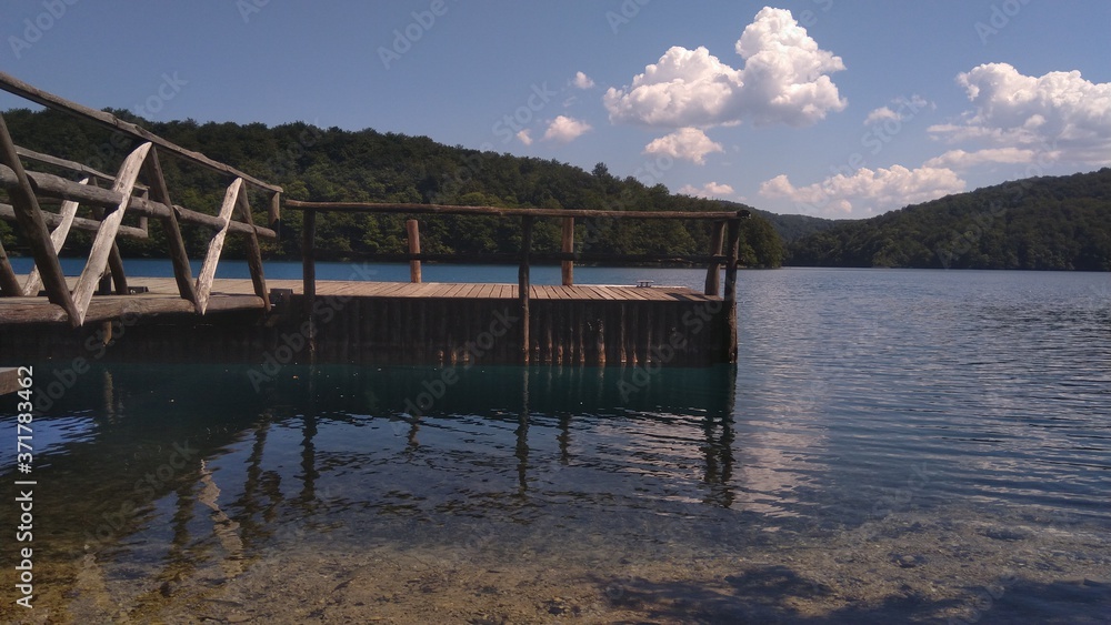 Wooden fishing pier in the clear lake water