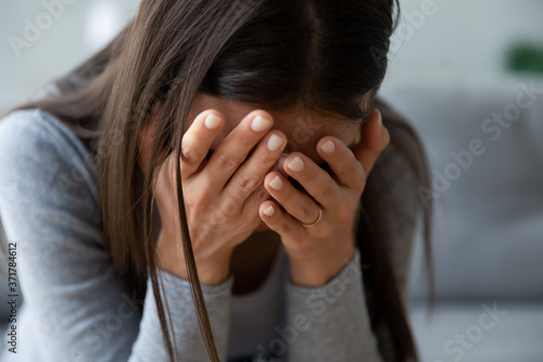 Foto Close up unhappy young woman hiding face in hands, feeling desperate cheated hopeless alone indoors