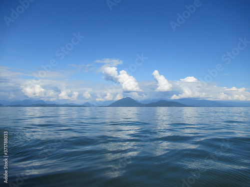Beautiful landscape with sea, mountains and white clouds on blue sky near Vancouver.