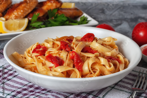 Pasta with tomatoes and grilled wings. Italian food. Italian Cuisine. The concept of tasty and healthy food.