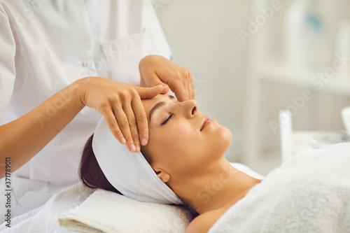 Woman face massage. A professional beautician makes massage treatments for a client in a beauty salon.