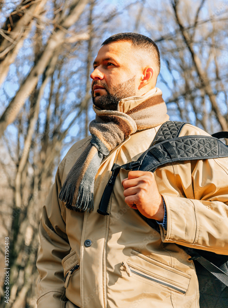 Obraz premium Beard man in the park. Young traveler in the forest. Lonely man with backpack and jacket. Adult serious man with black beard in the autumn park.