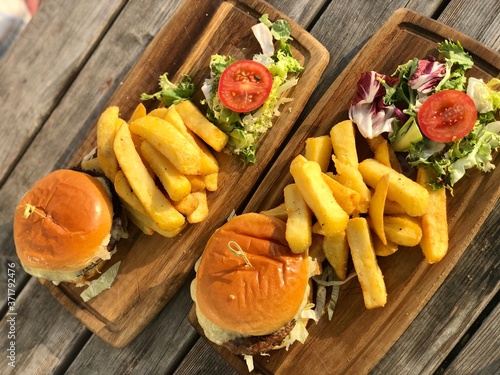 Burger, hamburger with french fries, ketchup, mustard and fresh vegetables on a cutting wooden board.