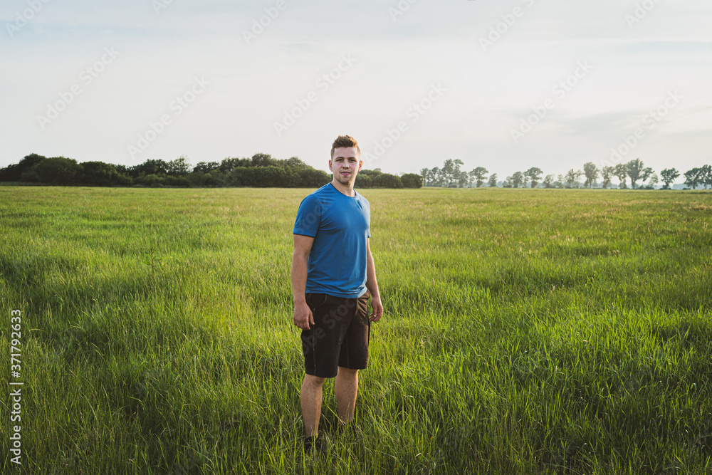 Landwirtschaft - Grünlandwirtschaft, junger Landwirt steht am Abend auf einer großen Wiese. Landwirtschaft - Grünlandwirtschaft, junger Landwirt steht am Abend auf einer großen Wiese.